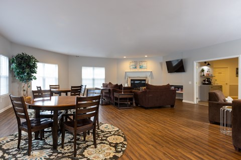 A living room with a brown couch, a wooden table and chairs, and a television.