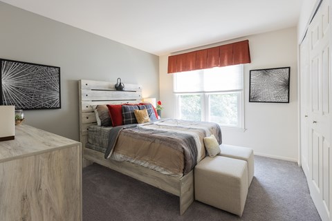 A bedroom with a large bed and a window with red curtains.