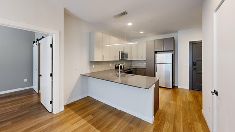 A modern kitchen with a wooden floor and white walls.