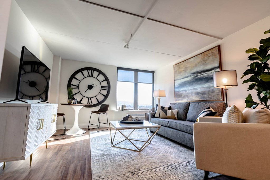 A living room with a grey couch, a coffee table, and a large painting on the wall at Cityplace Apartment Homes Apartments, Pennsylvania