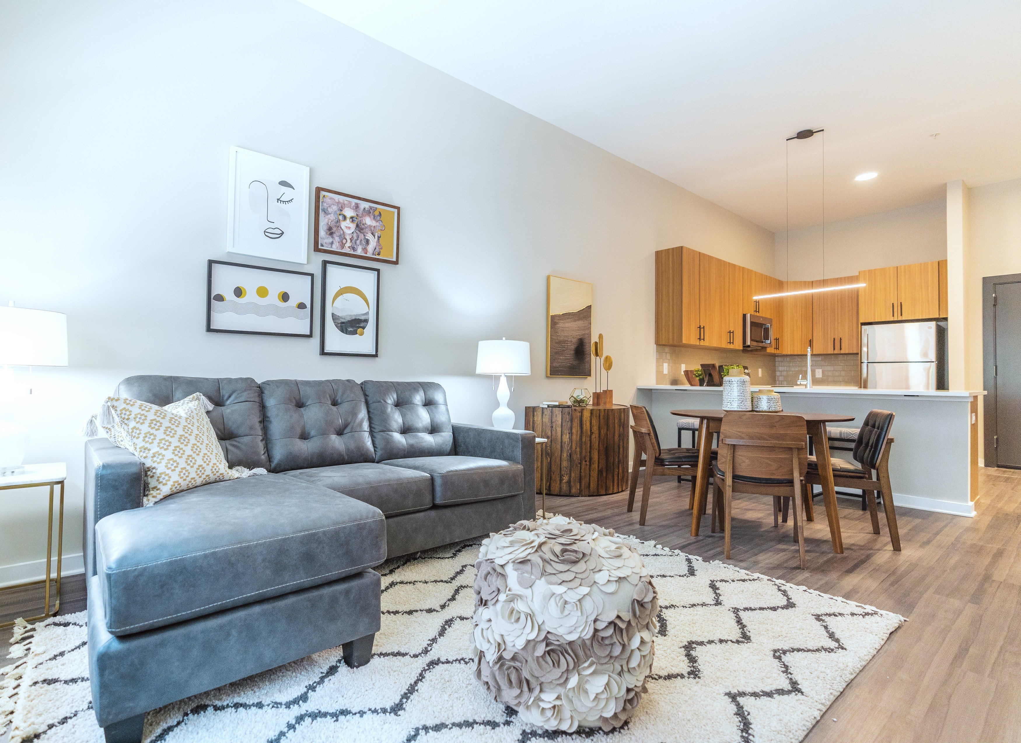 A modern living room with a grey sofa and a black and white rug.