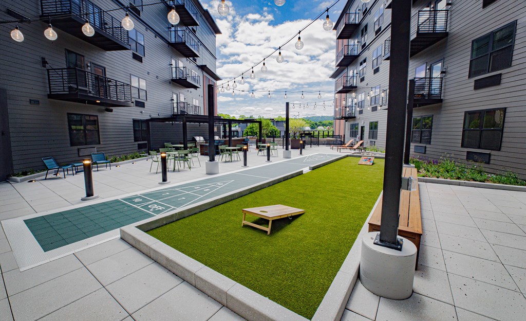 A patio area with a green lawn and a wooden bench.