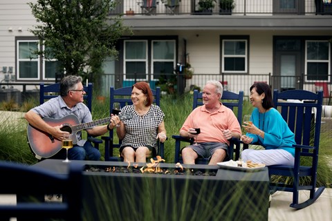 Four people are sitting around a table playing guitar and singing.