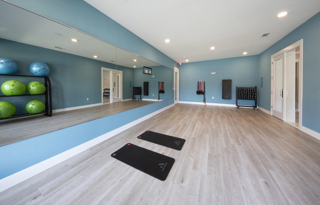 a fitness room with a large mirror and fitness equipment at a senior apartment community