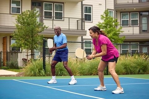 A man and a woman playing tennis on a blue court.