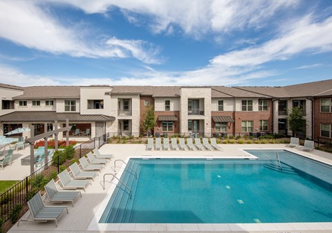a resort-style pool with lounge chairs at a senior apartment community