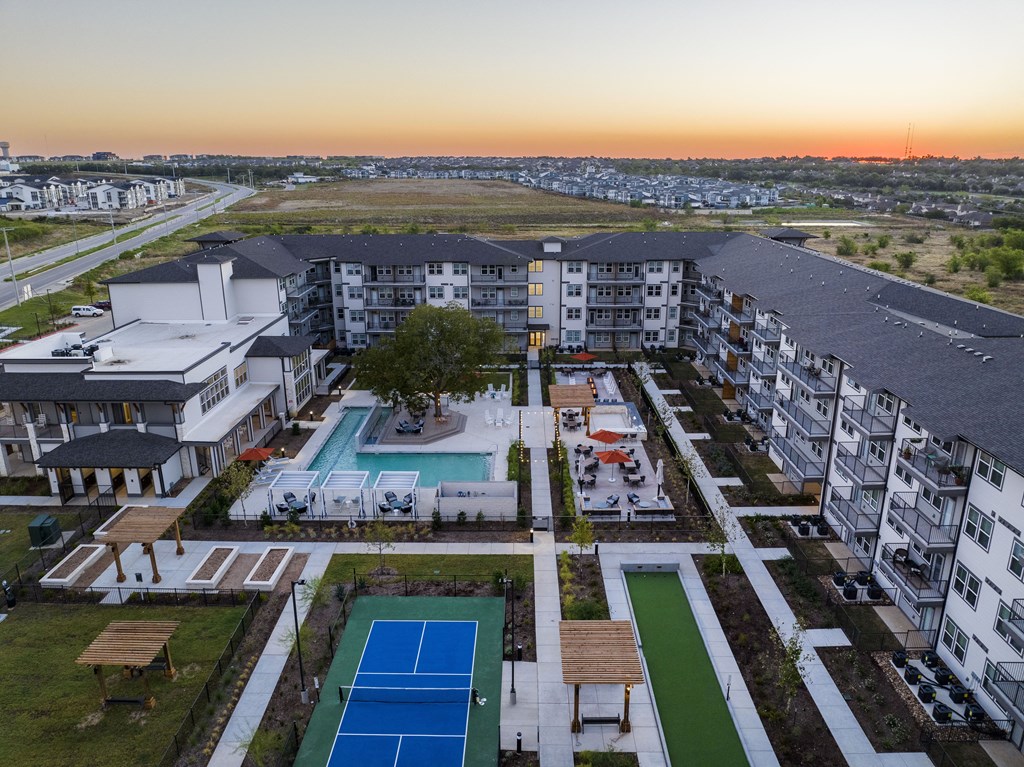 an aerial view of an apartment complex with a pool and tennis court