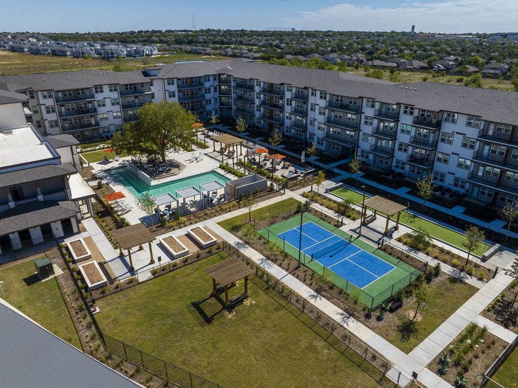 an overhead view of a building with two tennis courts and a pool