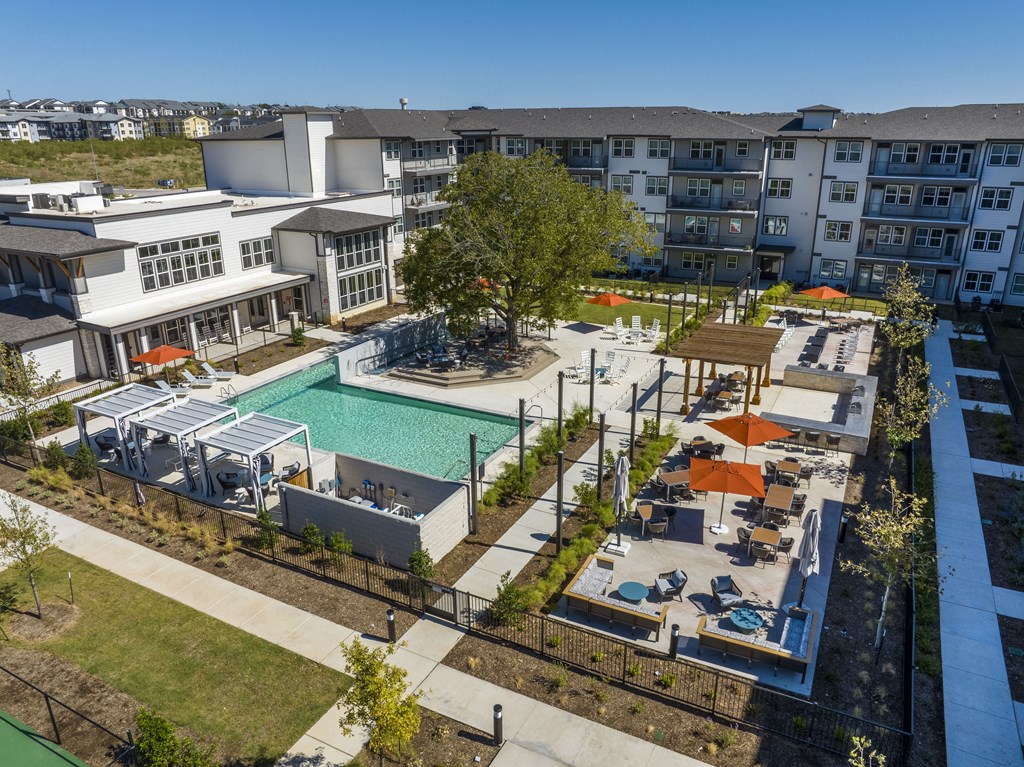 an aerial view of an apartment complex with a pool and lounge areas