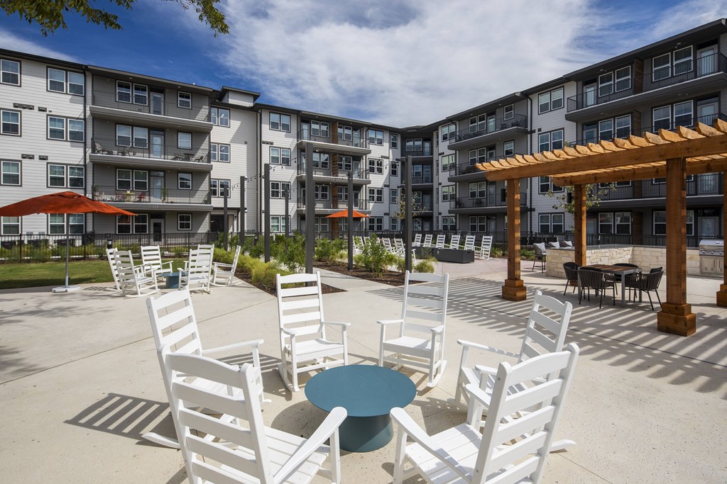an outdoor patio with white chairs and tables and an apartment building