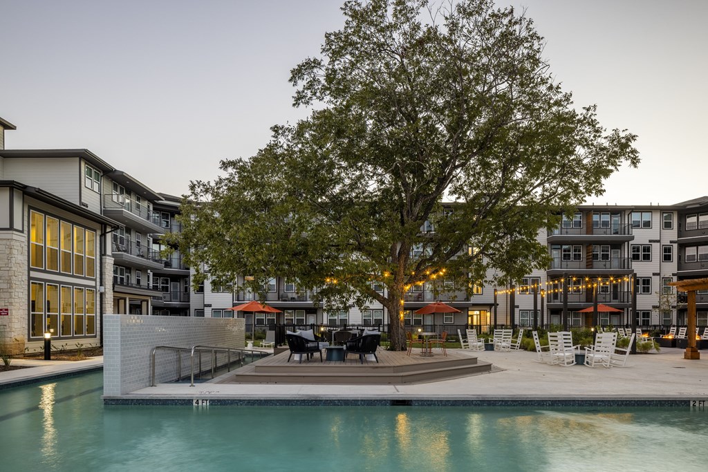 a swimming pool with a tree in the middle of an apartment complex