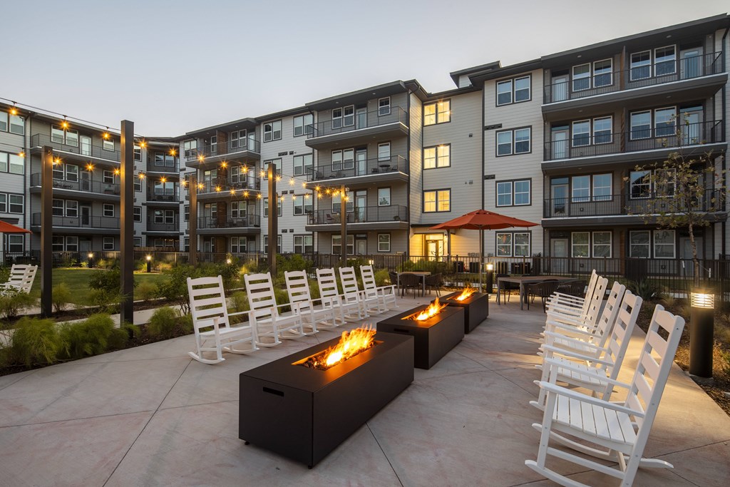 an outdoor patio with chairs and fire pits at dusk