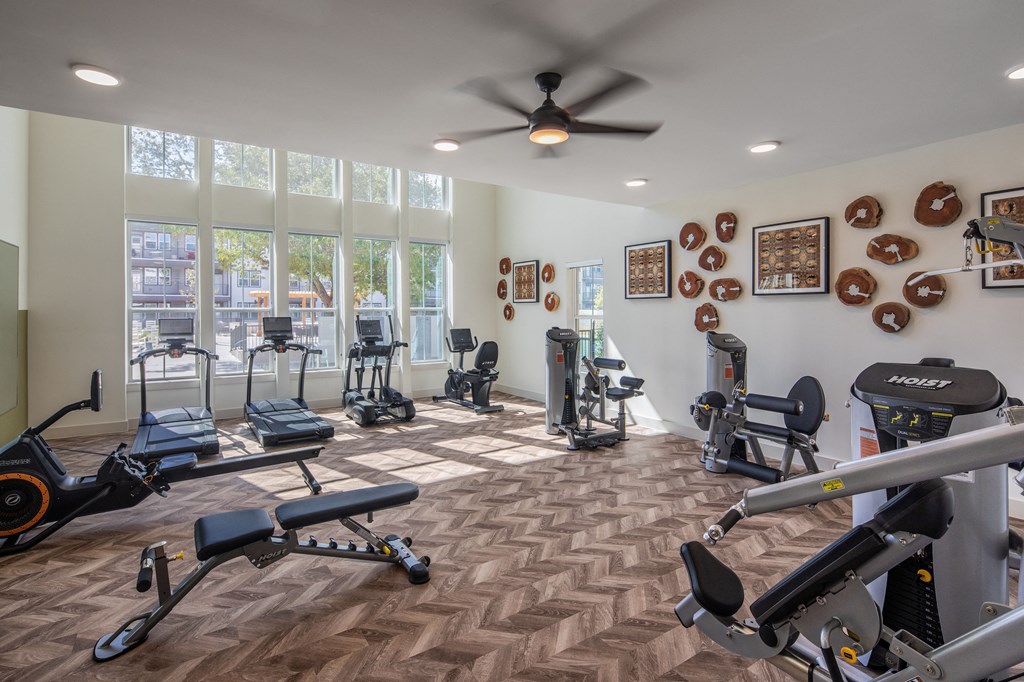 a gym with exercise machines and windows and a ceiling fan