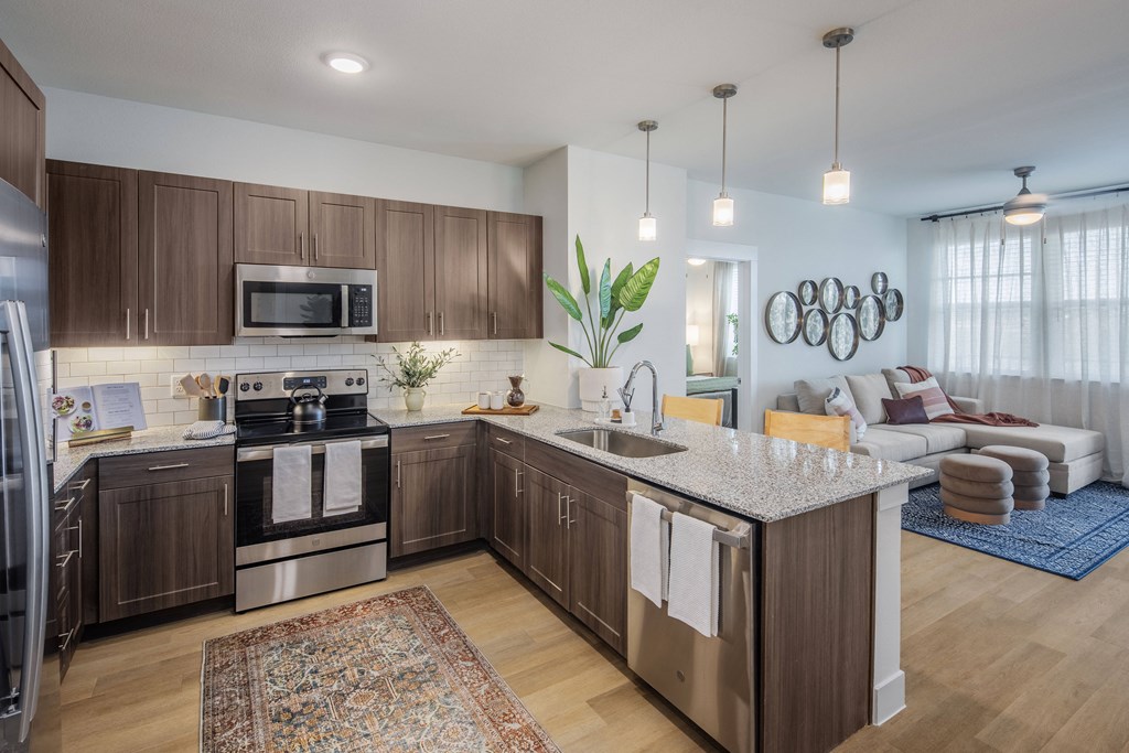 a kitchen and living room with a granite counter top at a senior apartment complex