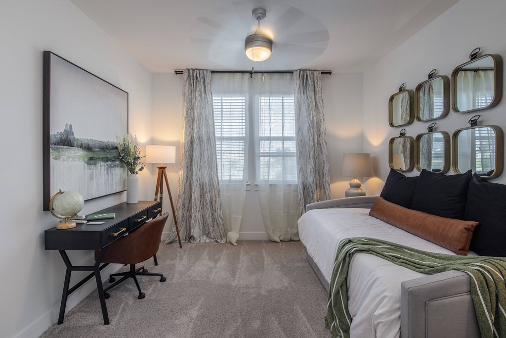 a bedroom with a bed and a desk and a window