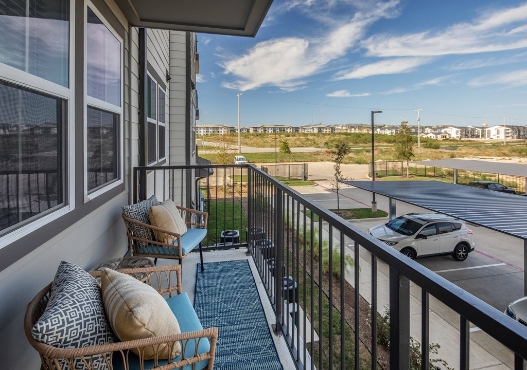 a balcony with a couch and chairs and a view of a parking lot