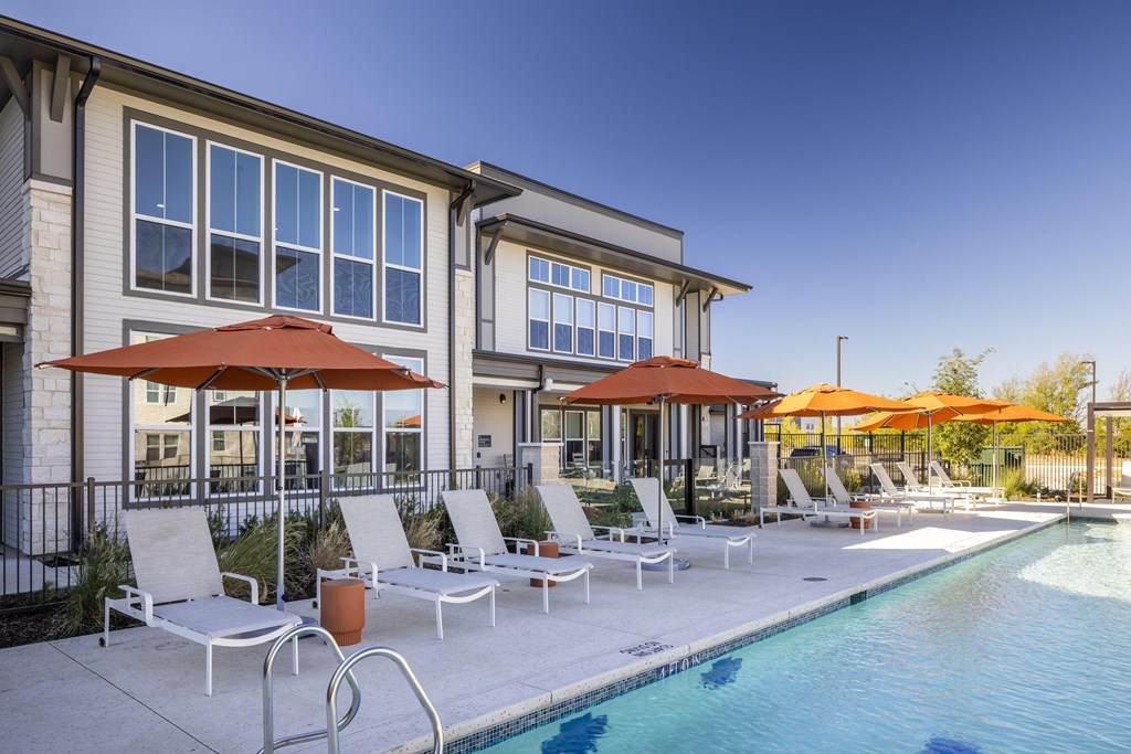 a swimming pool with chairs and umbrellas in front of a building