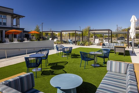 a lounge area with tables and chairs on the grass