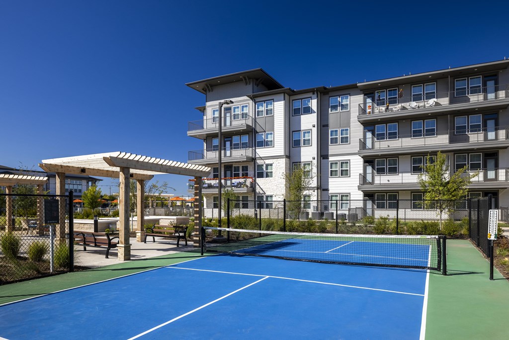 a tennis court with an apartment building in the background