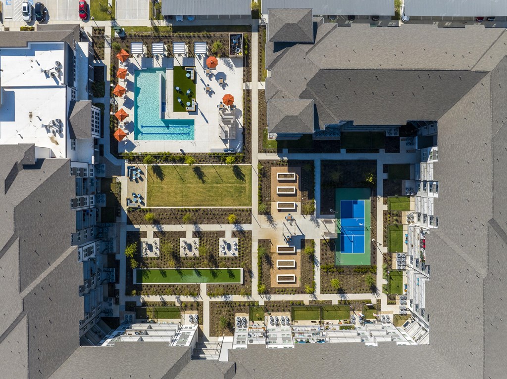 arial view of a building with lawns and a tennis court on the roof