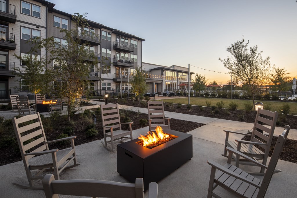 an outdoor patio with chairs and a fire pit at dusk