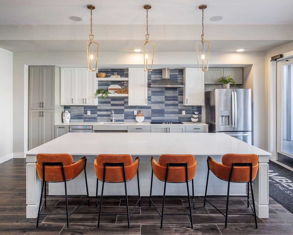 a kitchen with a large white island and orange chairs