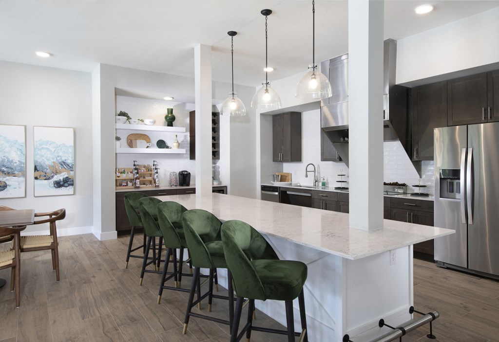 a communal clubhouse kitchen with a large island and seating at a senior apartment community