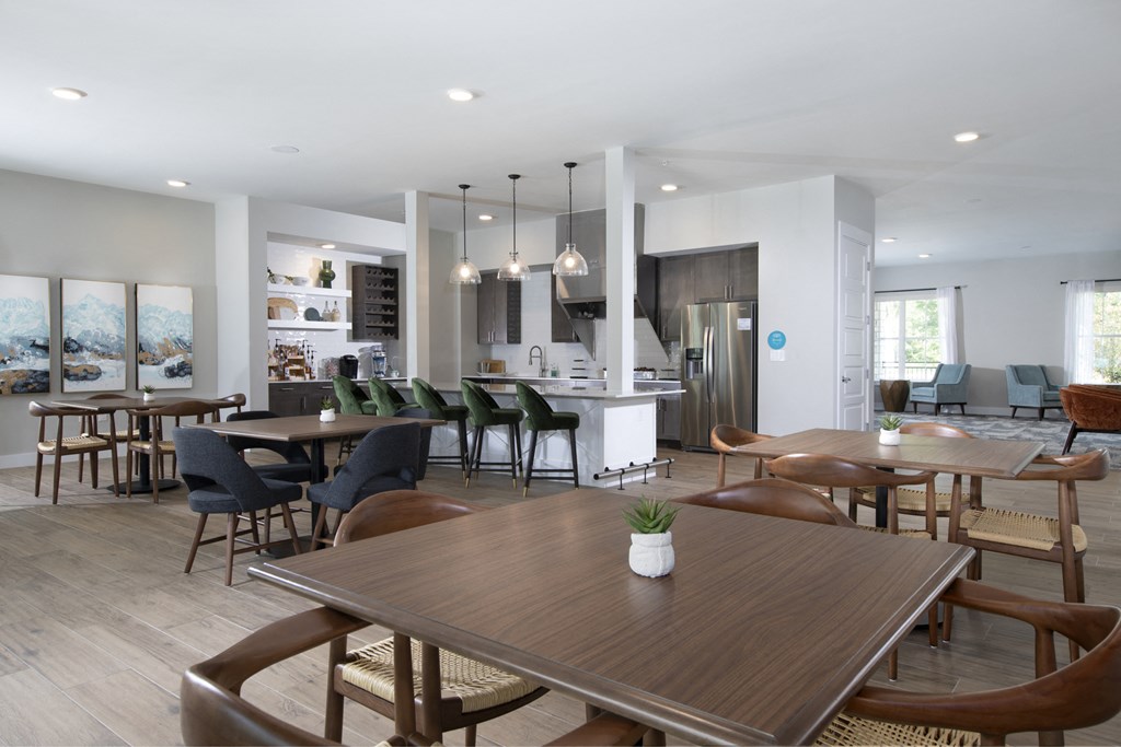 a communal clubhouse dining room opening up to a kitchen at a senior apartment community
