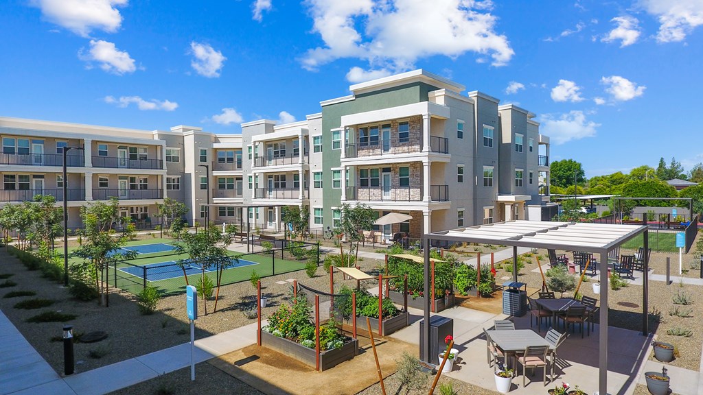 A modern apartment complex with a pool and outdoor seating area.