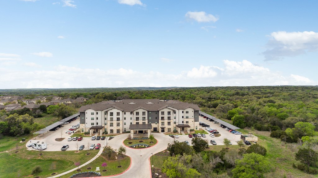 an aerial view of an apartment complex with parking lot and trees