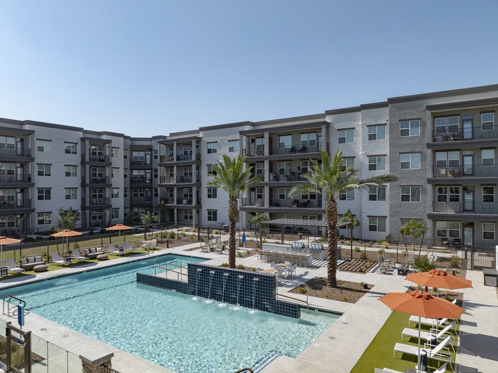 a swimming pool with palm trees in front of an apartment building