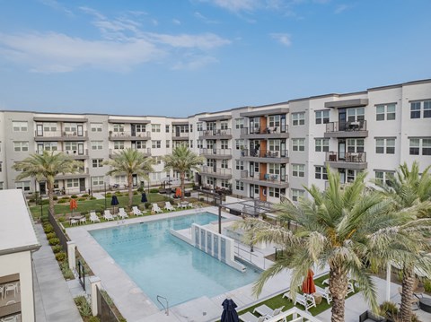 a large pool with palm trees in front of an apartment building
