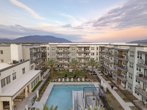 an aerial view of an apartment complex with a pool and palm trees