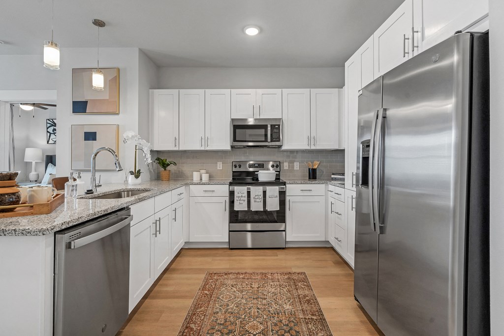 a kitchen with stainless steel appliances and granite countertops at a senior apartment community