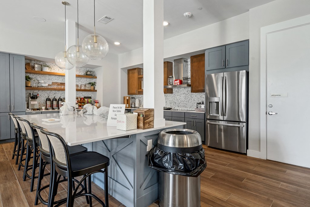 a communal clubhouse kitchen with a large island and chairs at a senior apartment community