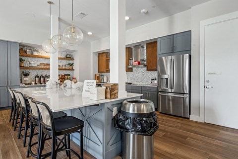 a communal clubhouse kitchen with a large island and chairs at a senior apartment community