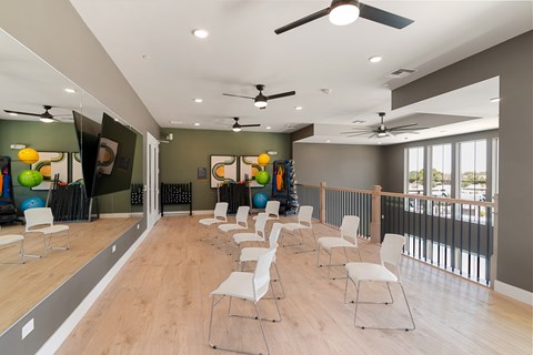 A room with a row of white chairs and a mirror on the wall.