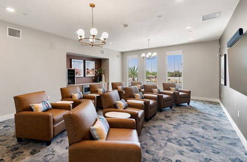 A living room with brown leather chairs and a chandelier.
