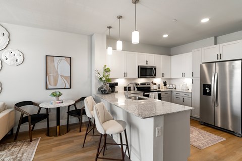 A kitchen with a table and chairs in the foreground and a refrigerator in the background.