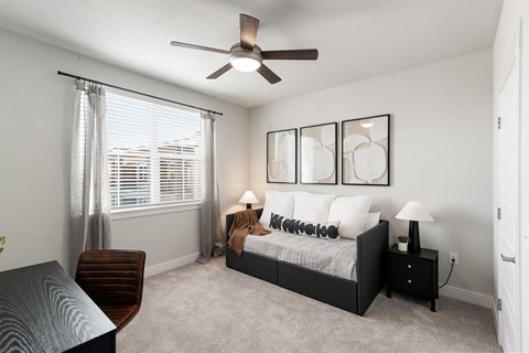 A bedroom with a bed, nightstand, and a ceiling fan.
