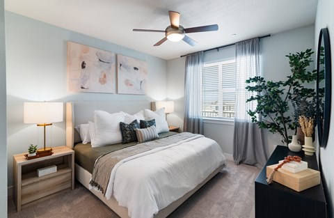 A bedroom with a bed, nightstand, and a ceiling fan.