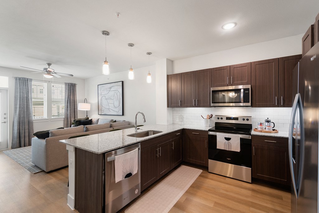 a kitchen and living room with stainless steel appliances and wooden cabinets
