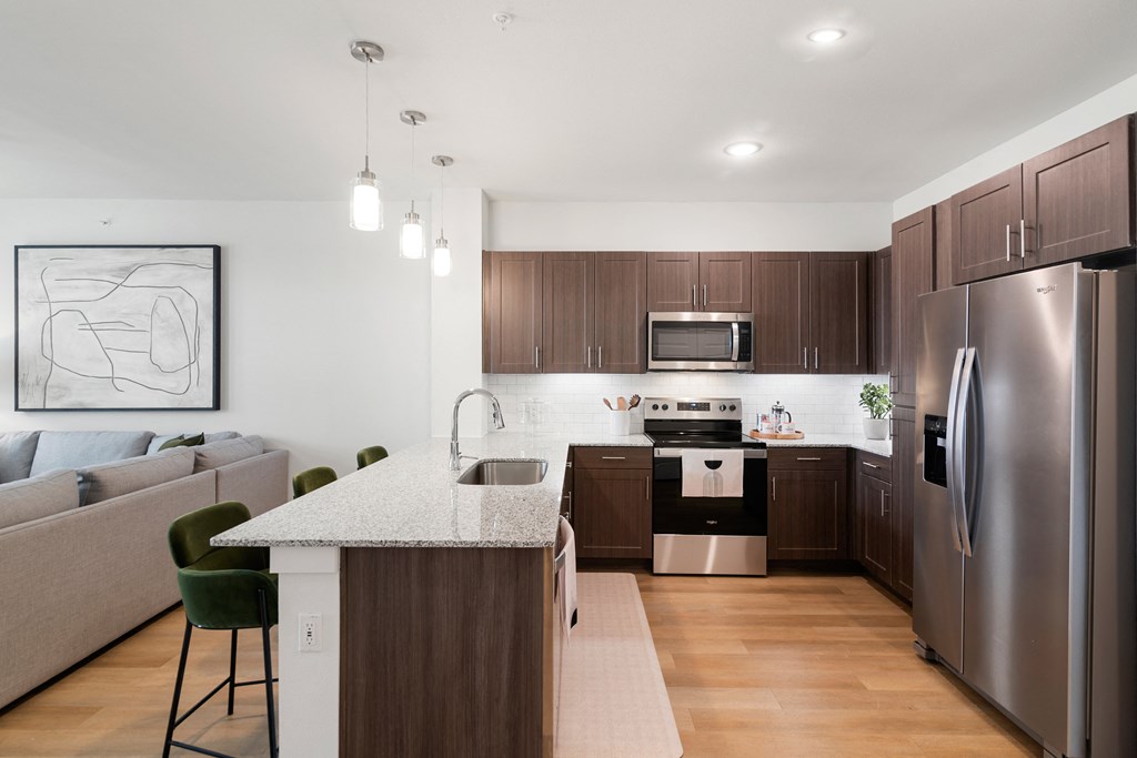 a kitchen and living room with stainless steel appliances and a marble counter top