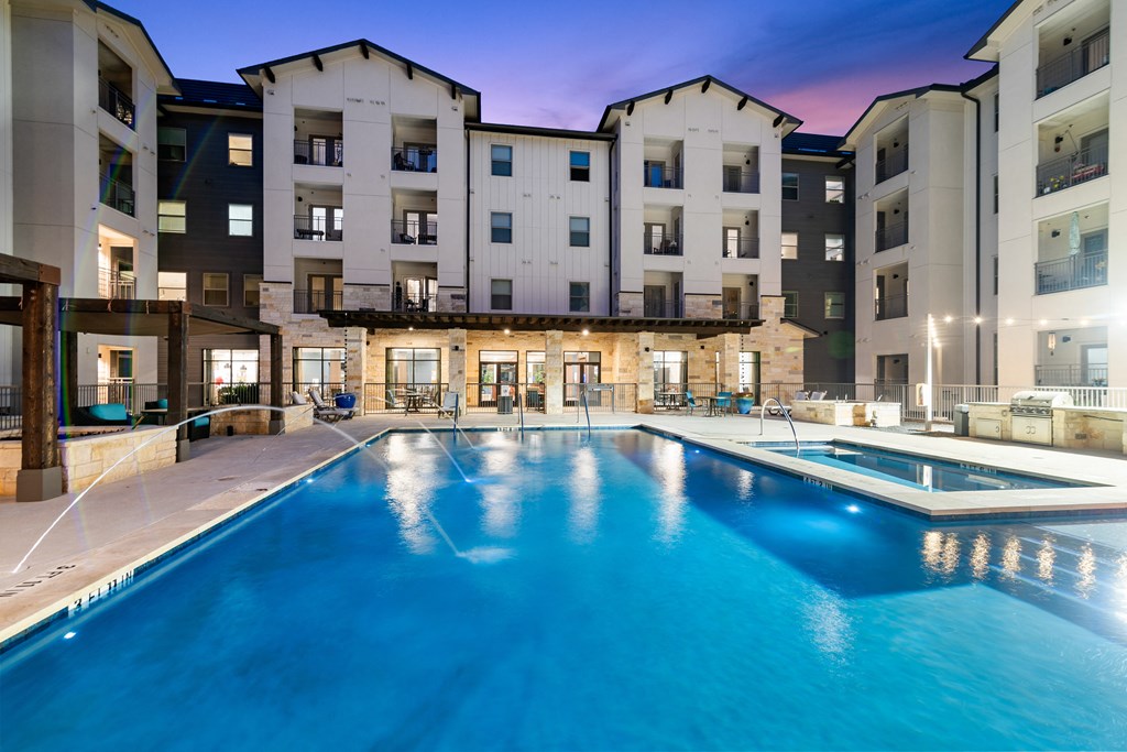 a swimming pool with buildings in the background at dusk