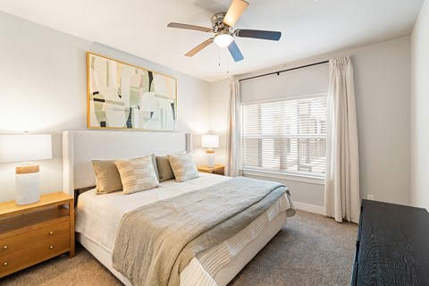 A bedroom with a bed, nightstand, and a painting on the wall.