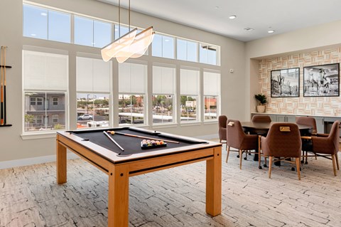 a billiards table in a clubhouse with a dining table and chairs