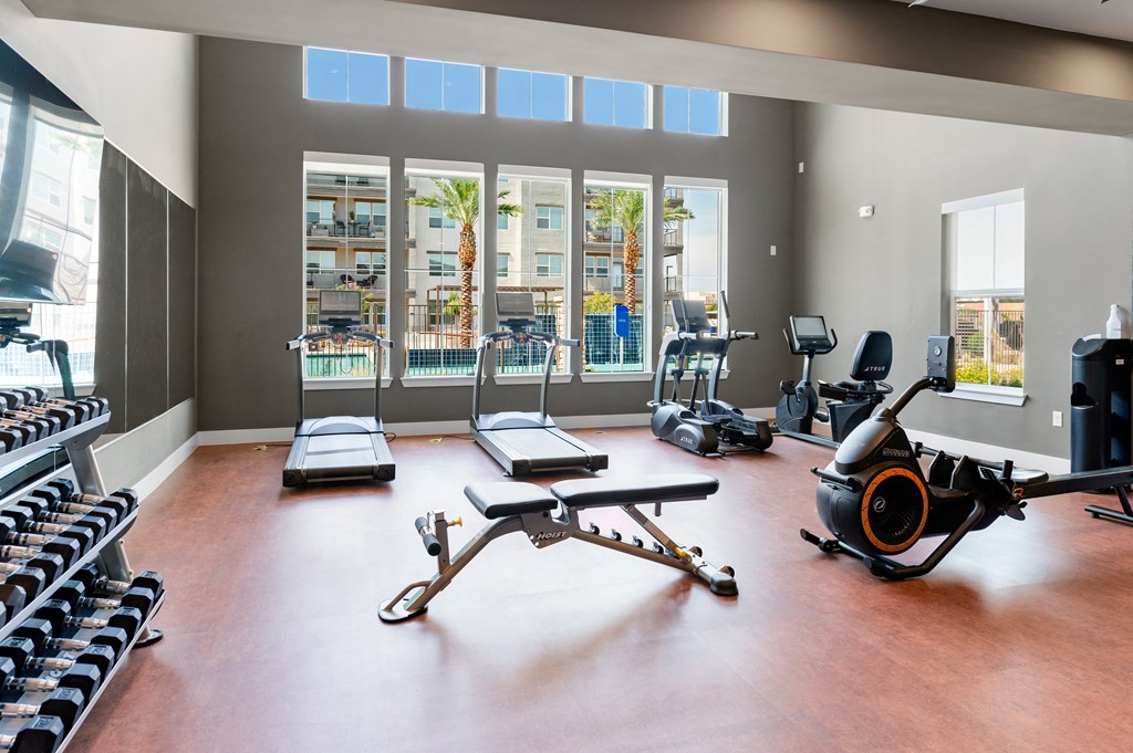 a workout room with weights and other exercise equipment and windows