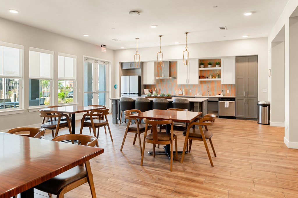 an open kitchen and dining area with wooden tables and chairs