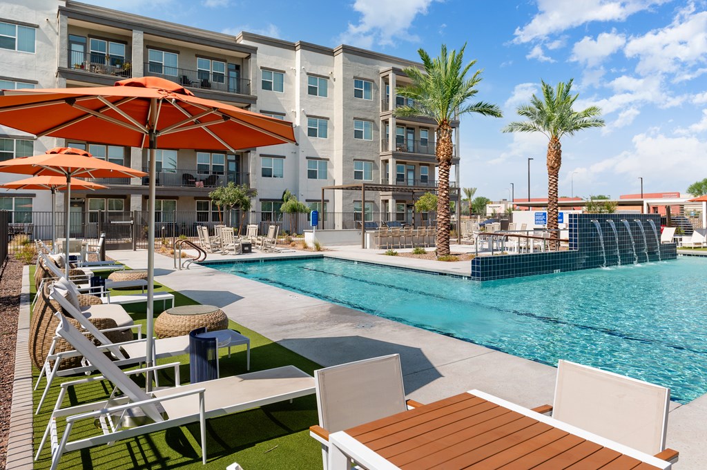 a swimming pool with tables and umbrellas in front of a building