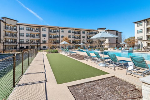 a bocce ball court stationed behind lounge chairs and umbrellas at a senior apartment community